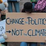 person holding change the politics not the climate printed board