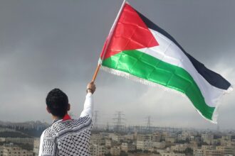 man waving flag আয়ারল্যান্ড, স্পেন ও নরওয়ের প্যালেস্টাইন রাষ্ট্রকে স্বীকৃতি দেওয়ার ঘোষণা